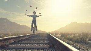 Man riding unicycle on a train track while juggling